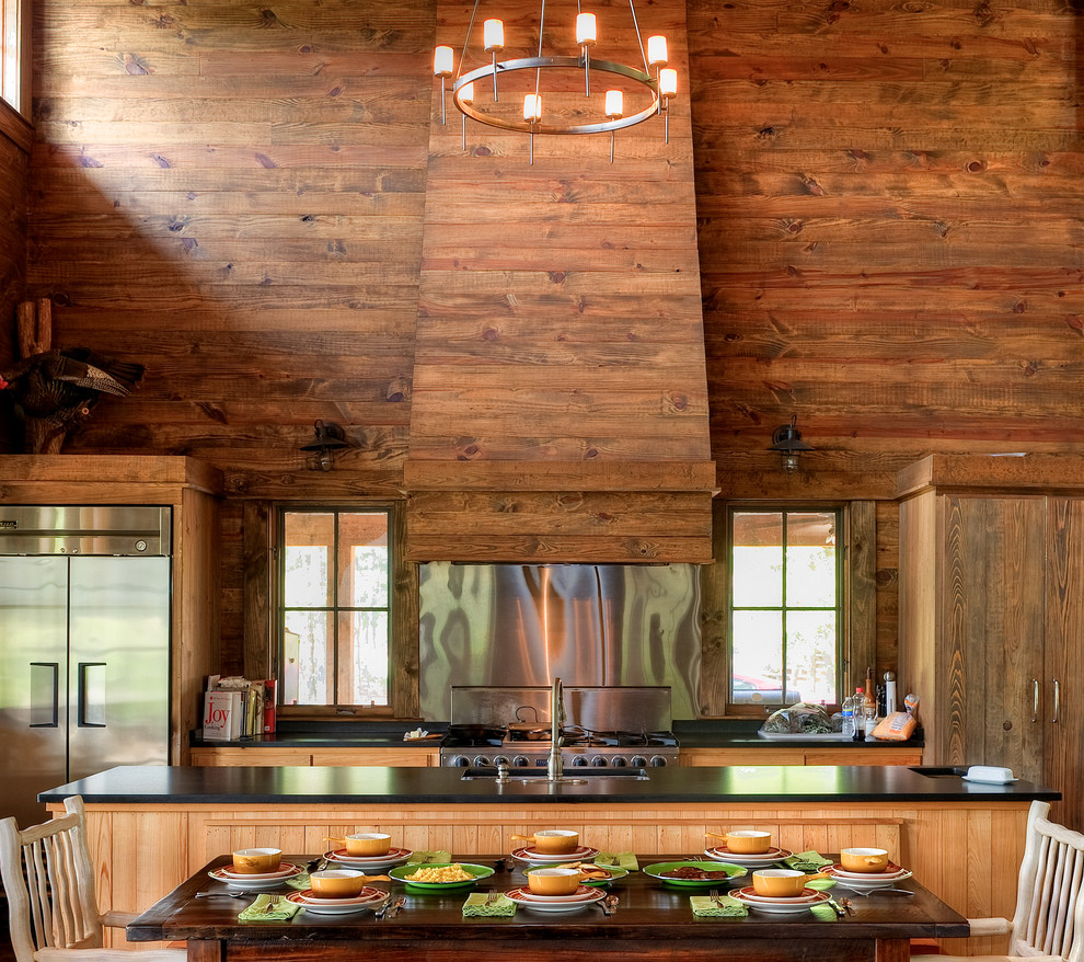 Foto de cocina comedor rural con fregadero bajoencimera, puertas de armario de madera oscura, salpicadero metalizado, electrodomésticos de acero inoxidable y una isla