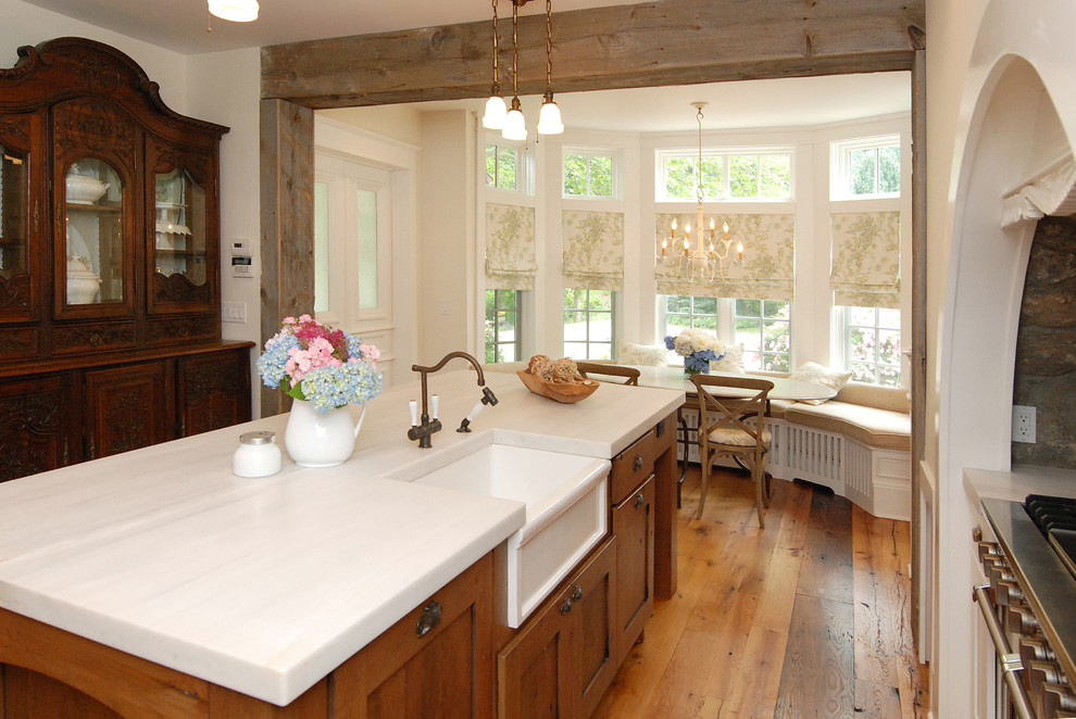 This is an example of a rustic kitchen/diner in New York with a belfast sink, shaker cabinets, medium wood cabinets, marble worktops and stainless steel appliances.