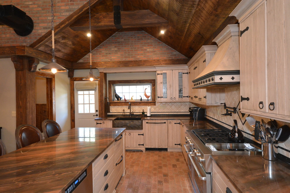 This is an example of a large rustic l-shaped kitchen/diner in New York with a belfast sink, beige cabinets, quartz worktops, beige splashback, limestone splashback, stainless steel appliances, brick flooring, an island and orange floors.