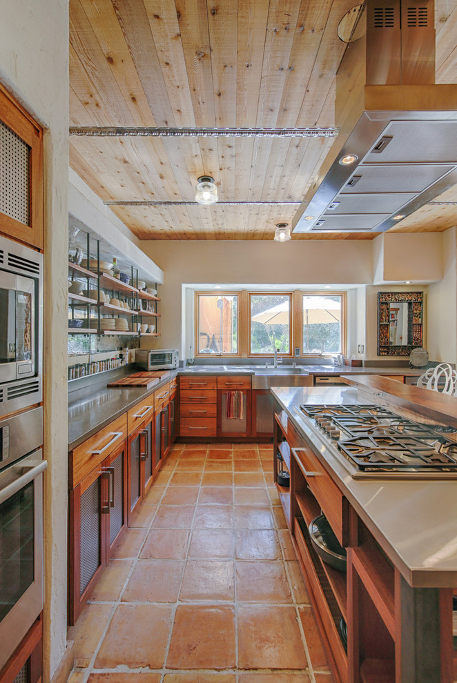 Foto di un cucina con isola centrale rustico con lavello stile country, ante in legno scuro, elettrodomestici in acciaio inossidabile e pavimento arancione