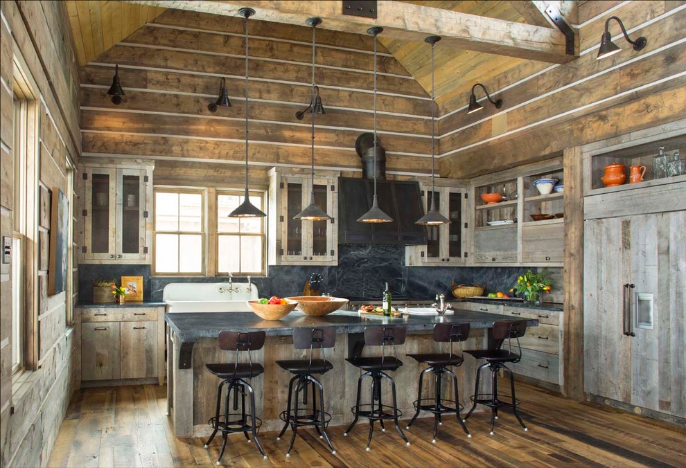 This is an example of a rustic kitchen in Denver with a belfast sink, flat-panel cabinets, white cabinets, black splashback, stone slab splashback, dark hardwood flooring, an island and integrated appliances.