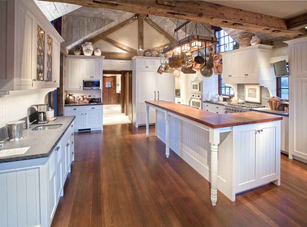 Bild på ett rustikt kök, med luckor med infälld panel, vita skåp, träbänkskiva och rostfria vitvaror