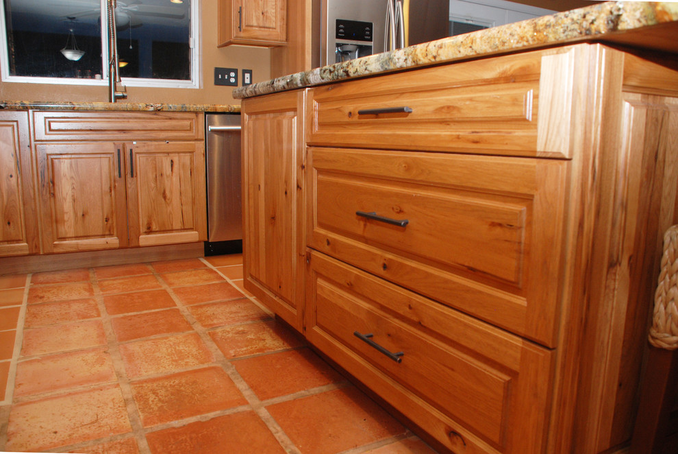 Bild på ett mellanstort rustikt kök, med en undermonterad diskho, luckor med upphöjd panel, skåp i mellenmörkt trä, granitbänkskiva, rostfria vitvaror, klinkergolv i terrakotta och en köksö