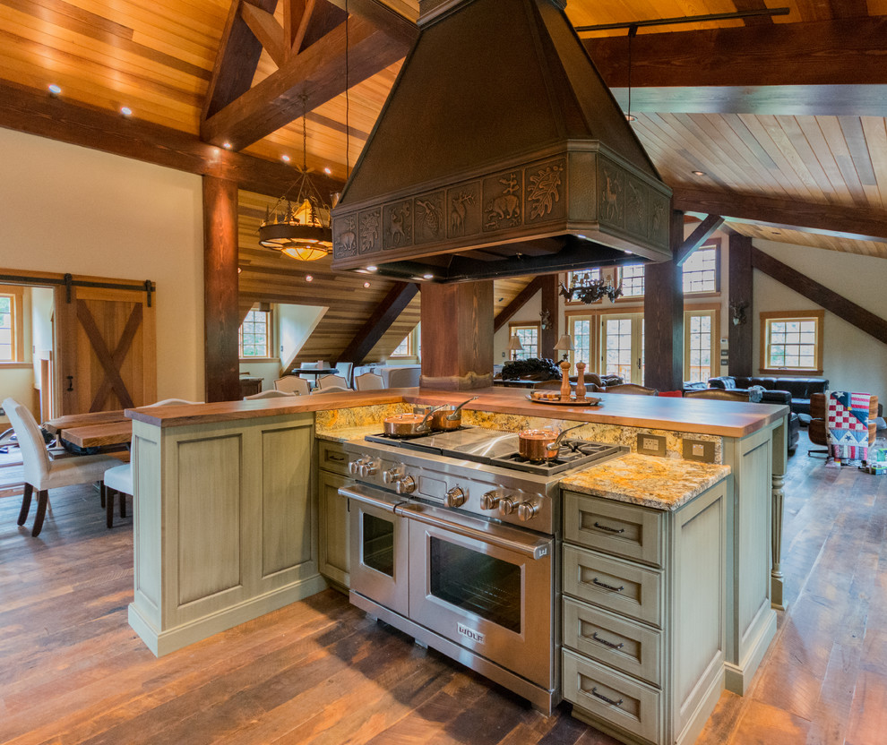 Bild på ett stort rustikt kök, med en rustik diskho, luckor med infälld panel, skåp i slitet trä, granitbänkskiva, stänkskydd i sten, rostfria vitvaror, mörkt trägolv och en köksö