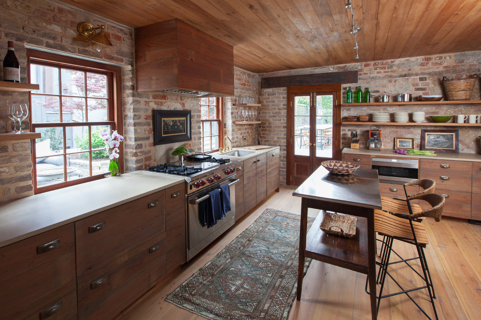 Medium sized rustic l-shaped kitchen in Charleston with a submerged sink, flat-panel cabinets, medium wood cabinets, stainless steel appliances, medium hardwood flooring and an island.