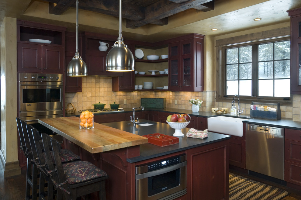Immagine di una cucina stile rurale con lavello stile country, ante in legno bruno, paraspruzzi con piastrelle in pietra, elettrodomestici in acciaio inossidabile, paraspruzzi beige e struttura in muratura