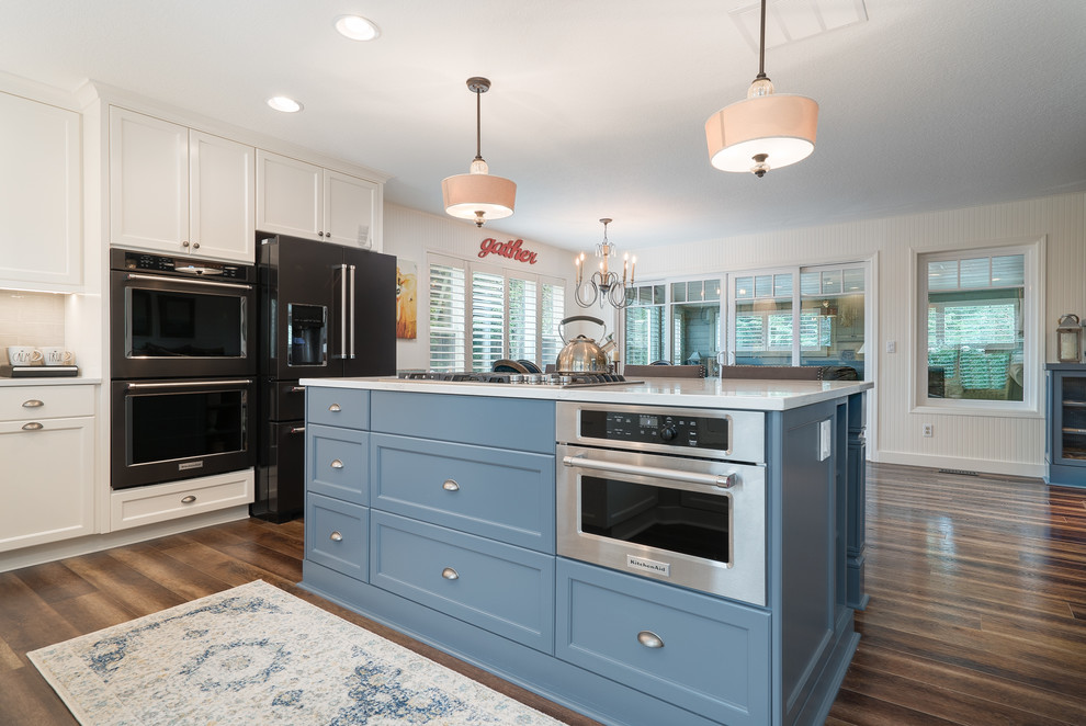 Example of a mid-sized cottage l-shaped medium tone wood floor eat-in kitchen design in Portland with white cabinets and an island