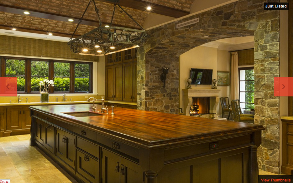 Immagine di un'ampia cucina rustica con lavello a doppia vasca, ante in legno bruno, top in marmo, paraspruzzi marrone e pavimento in travertino