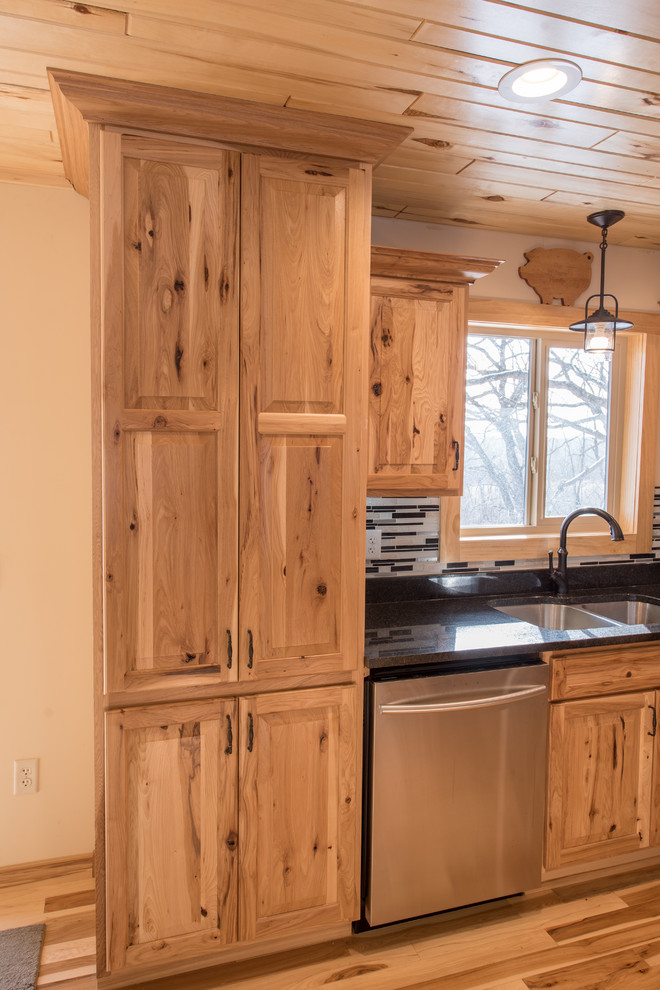 Inredning av ett rustikt mellanstort kök, med en dubbel diskho, luckor med upphöjd panel, skåp i ljust trä, granitbänkskiva, flerfärgad stänkskydd, stänkskydd i stickkakel, rostfria vitvaror, ljust trägolv och en köksö