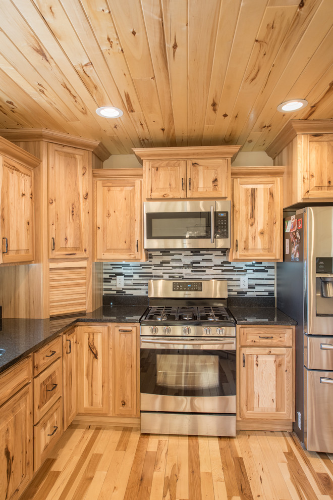 Bild på ett mellanstort rustikt kök, med en dubbel diskho, luckor med upphöjd panel, skåp i ljust trä, granitbänkskiva, flerfärgad stänkskydd, stänkskydd i stickkakel, rostfria vitvaror, ljust trägolv och en köksö