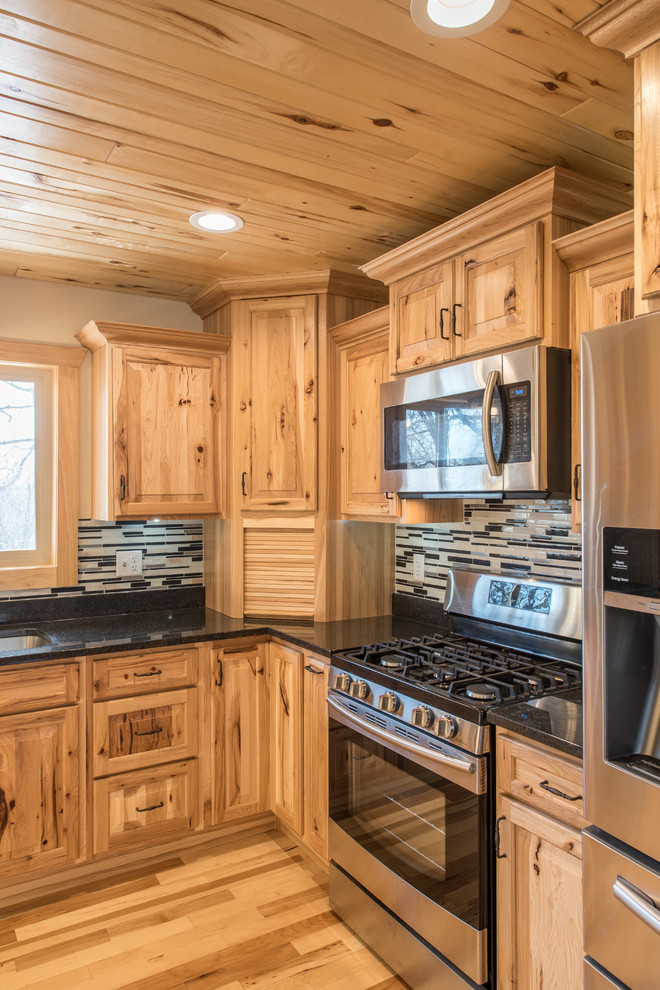 Inredning av ett rustikt mellanstort kök, med en dubbel diskho, luckor med upphöjd panel, skåp i ljust trä, granitbänkskiva, flerfärgad stänkskydd, stänkskydd i stickkakel, rostfria vitvaror, ljust trägolv och en köksö