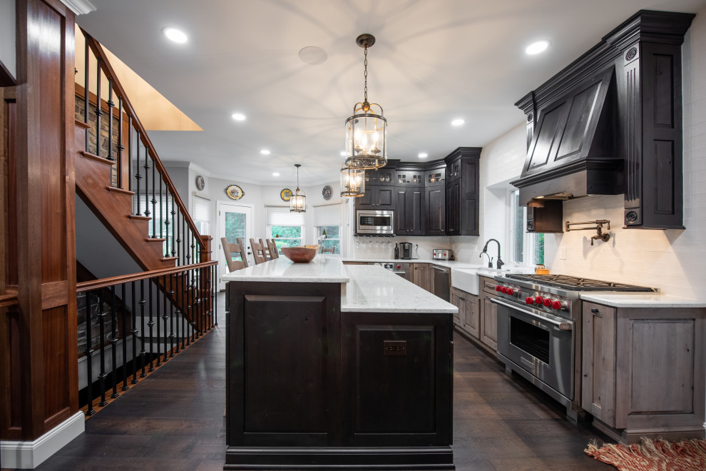 Example of a large mountain style u-shaped dark wood floor and brown floor eat-in kitchen design in Philadelphia with a farmhouse sink, raised-panel cabinets, medium tone wood cabinets, quartz countertops, white backsplash, subway tile backsplash, stainless steel appliances, an island and white countertops