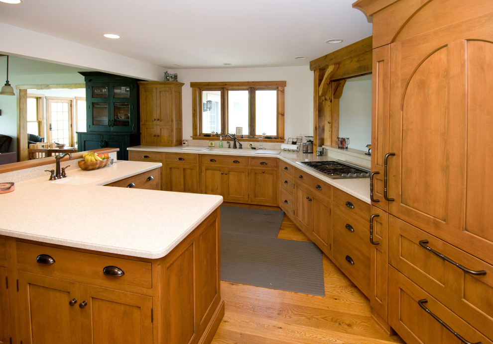 Inspiration for a large rustic l-shaped medium tone wood floor eat-in kitchen remodel in Other with an undermount sink, medium tone wood cabinets, solid surface countertops, white backsplash, paneled appliances, an island and flat-panel cabinets