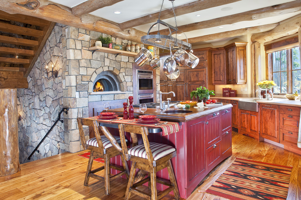 Mittelgroße Urige Küche in U-Form mit Landhausspüle, roten Schränken, profilierten Schrankfronten, Arbeitsplatte aus Holz, hellem Holzboden, Kücheninsel und Mauersteinen in Denver
