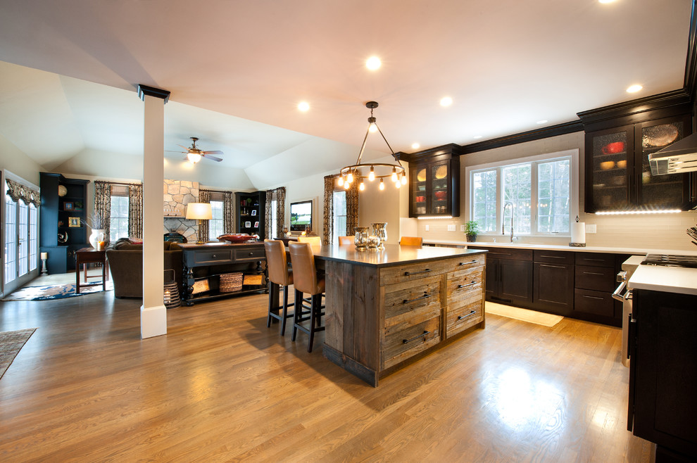 Huge mountain style l-shaped light wood floor open concept kitchen photo in Boston with an undermount sink, flat-panel cabinets, dark wood cabinets, quartzite countertops, beige backsplash, glass tile backsplash, stainless steel appliances and an island