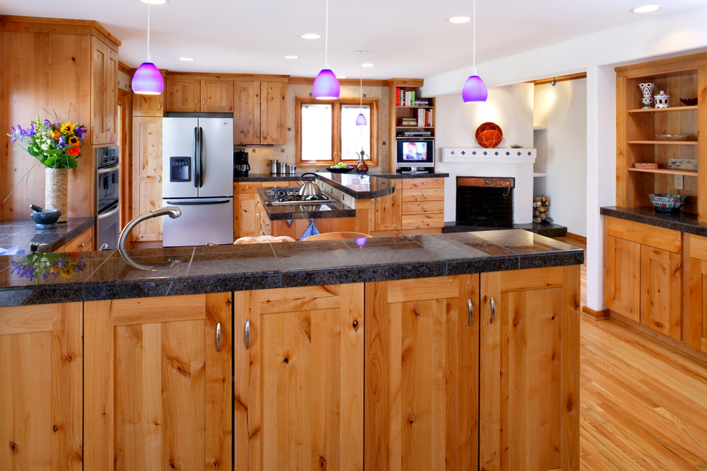 Mountain style u-shaped medium tone wood floor eat-in kitchen photo in Denver with a drop-in sink, shaker cabinets, tile countertops, brown backsplash, metal backsplash, stainless steel appliances, an island and black countertops