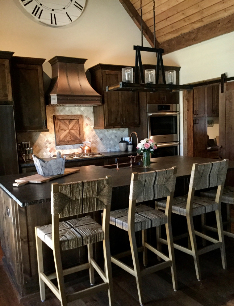 Exempel på ett litet rustikt svart svart kök, med en rustik diskho, skåp i shakerstil, skåp i mörkt trä, granitbänkskiva, beige stänkskydd, stänkskydd i kalk, rostfria vitvaror, mörkt trägolv, en köksö och brunt golv
