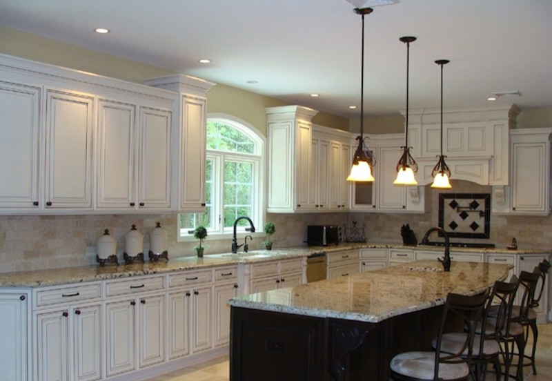 Foto på ett stort medelhavsstil beige kök, med en undermonterad diskho, luckor med upphöjd panel, vita skåp, granitbänkskiva, beige stänkskydd, stänkskydd i stenkakel, rostfria vitvaror, klinkergolv i porslin, flera köksöar och beiget golv