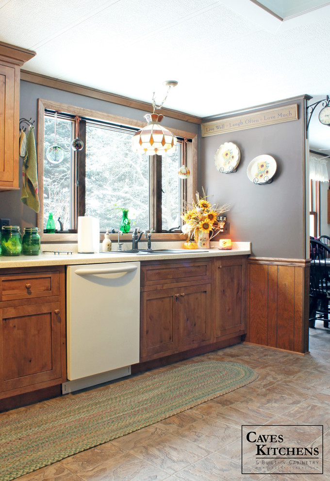 Inredning av ett rustikt avskilt, litet l-kök, med en nedsänkt diskho, luckor med infälld panel, skåp i mellenmörkt trä, bänkskiva i koppar, vita vitvaror och laminatgolv