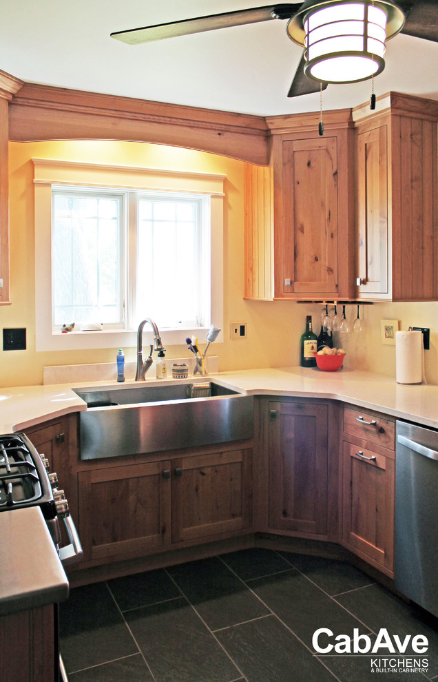 Bild på ett avskilt, litet rustikt u-kök, med en rustik diskho, luckor med infälld panel, skåp i mellenmörkt trä, bänkskiva i kvarts, rostfria vitvaror, skiffergolv och grått golv