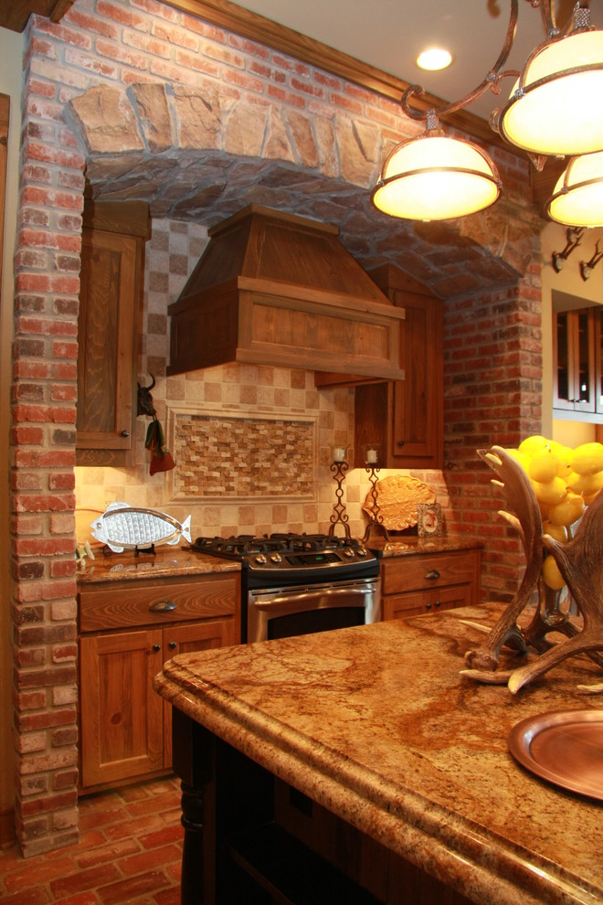 Bild på ett avskilt, stort rustikt l-kök, med luckor med infälld panel, skåp i mellenmörkt trä, granitbänkskiva, beige stänkskydd, stänkskydd i stenkakel, rostfria vitvaror, tegelgolv och en köksö