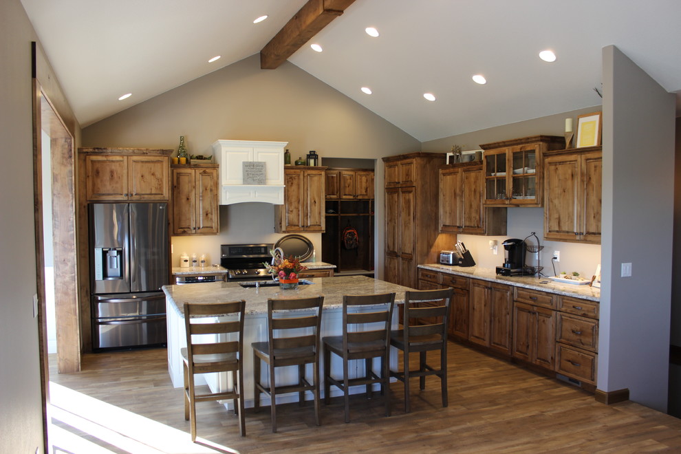 This is an example of a large rustic l-shaped open plan kitchen in Other with a submerged sink, raised-panel cabinets, medium wood cabinets, granite worktops, stainless steel appliances, medium hardwood flooring, an island and brown floors.