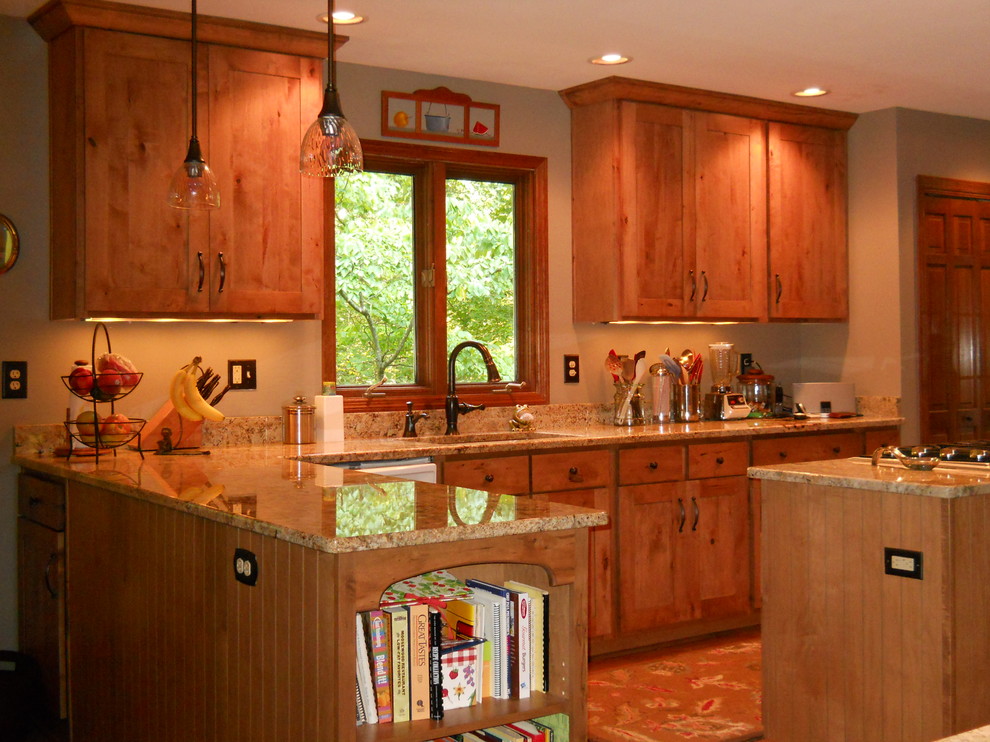 アトランタにあるコンテンポラリースタイルのおしゃれなキッチン (ダブルシンク、フラットパネル扉のキャビネット、中間色木目調キャビネット、御影石カウンター、シルバーの調理設備) の写真