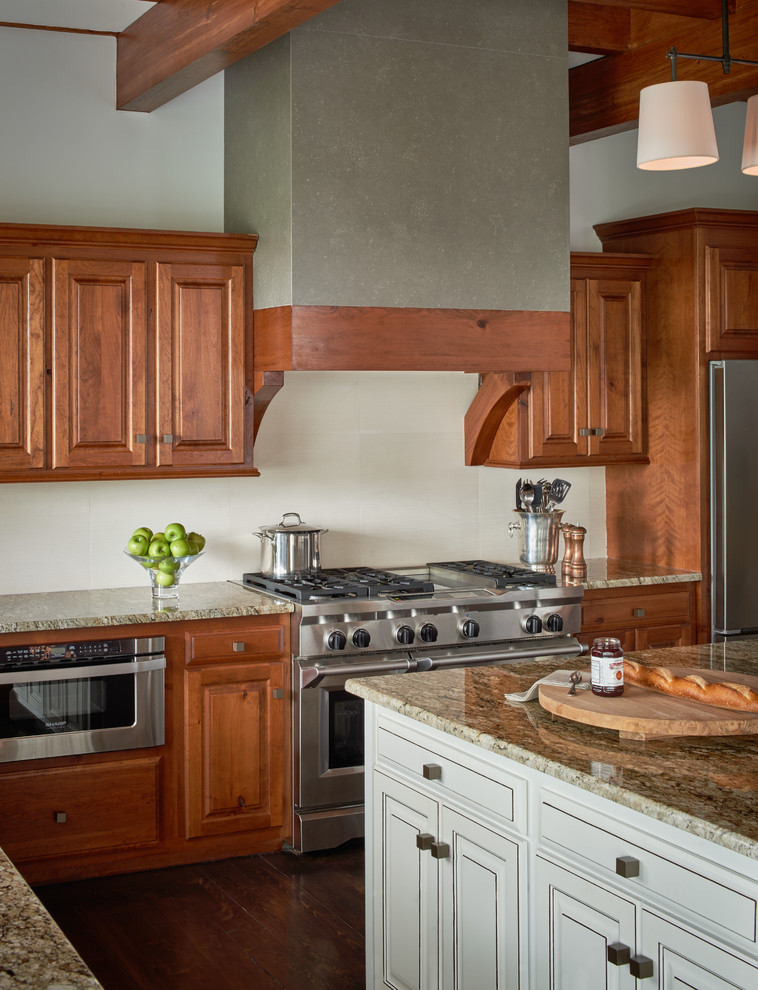Exemple d'une cuisine américaine parallèle montagne en bois brun de taille moyenne avec un placard avec porte à panneau surélevé, un plan de travail en granite, un électroménager en acier inoxydable, un sol en bois brun et îlot.