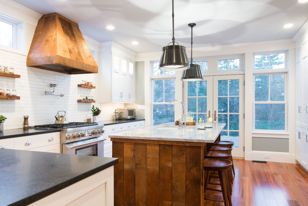 Cottage l-shaped medium tone wood floor kitchen photo in Boston with an undermount sink, shaker cabinets, white cabinets, white backsplash, subway tile backsplash, stainless steel appliances and an island