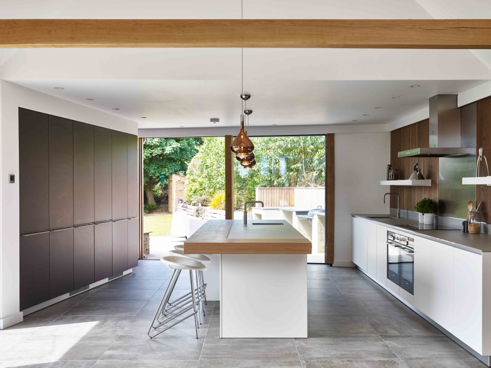 Cette image montre une grande cuisine ouverte bohème en bois foncé avec un placard à porte plane, une crédence métallisée, îlot et un plan de travail gris.