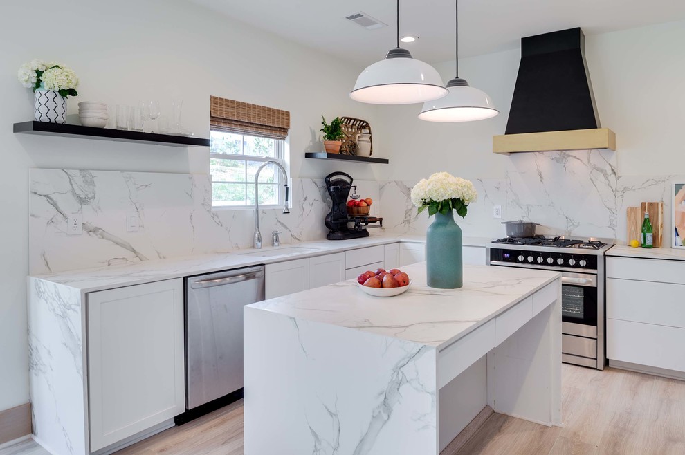 Foto på ett funkis l-kök, med en undermonterad diskho, vitt stänkskydd, stänkskydd i sten, rostfria vitvaror, ljust trägolv och en köksö