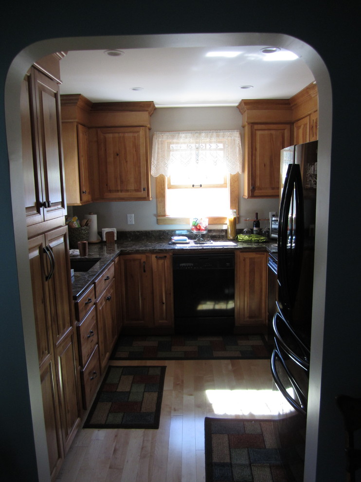 Foto på ett avskilt, mellanstort rustikt u-kök, med luckor med upphöjd panel, skåp i ljust trä, svarta vitvaror, en enkel diskho och bänkskiva i kvarts