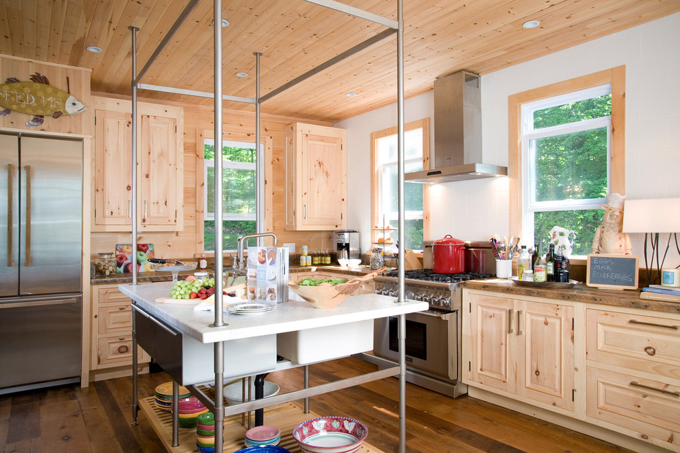 Ejemplo de cocina rústica de obra con electrodomésticos de acero inoxidable, armarios con paneles con relieve y puertas de armario de madera clara