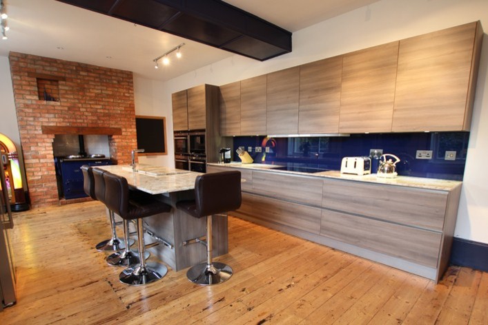 Aménagement d'une cuisine contemporaine en bois brun avec un plan de travail en granite, une crédence bleue et îlot.