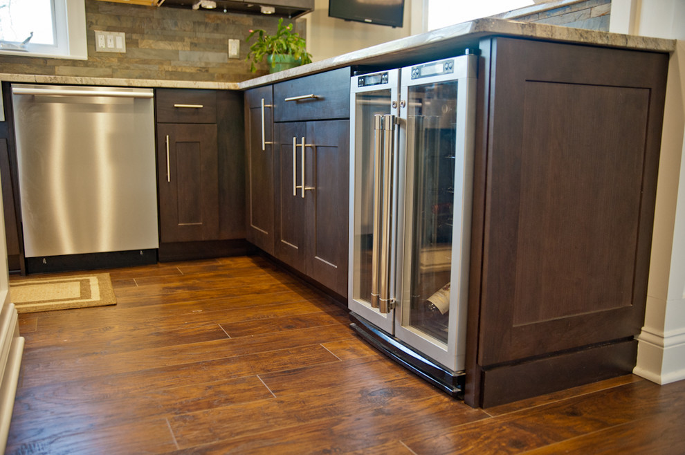 Example of a mid-sized trendy u-shaped dark wood floor kitchen pantry design in New York with a farmhouse sink, flat-panel cabinets, dark wood cabinets, granite countertops, multicolored backsplash, stone tile backsplash, stainless steel appliances and an island