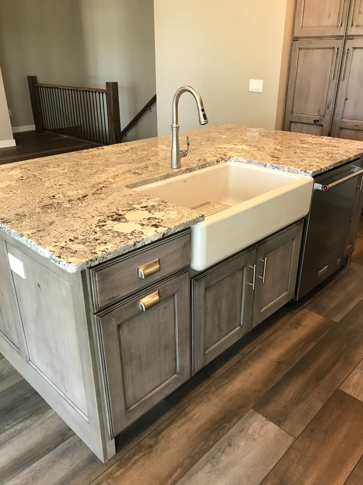 Medium sized farmhouse l-shaped open plan kitchen in Cedar Rapids with a belfast sink, flat-panel cabinets, distressed cabinets, stainless steel appliances and an island.