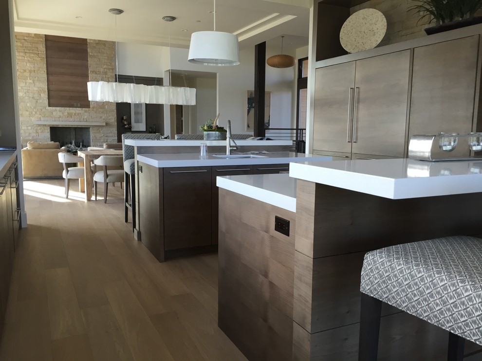 Inspiration for a large rustic galley light wood floor open concept kitchen remodel in Salt Lake City with flat-panel cabinets, medium tone wood cabinets, solid surface countertops, white backsplash, paneled appliances and two islands