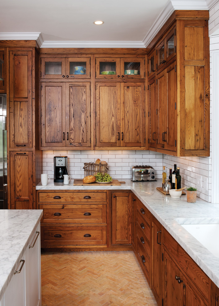 Inspiration för rustika l-kök, med en undermonterad diskho, luckor med infälld panel, skåp i mellenmörkt trä, granitbänkskiva, vitt stänkskydd, stänkskydd i tunnelbanekakel och tegelgolv