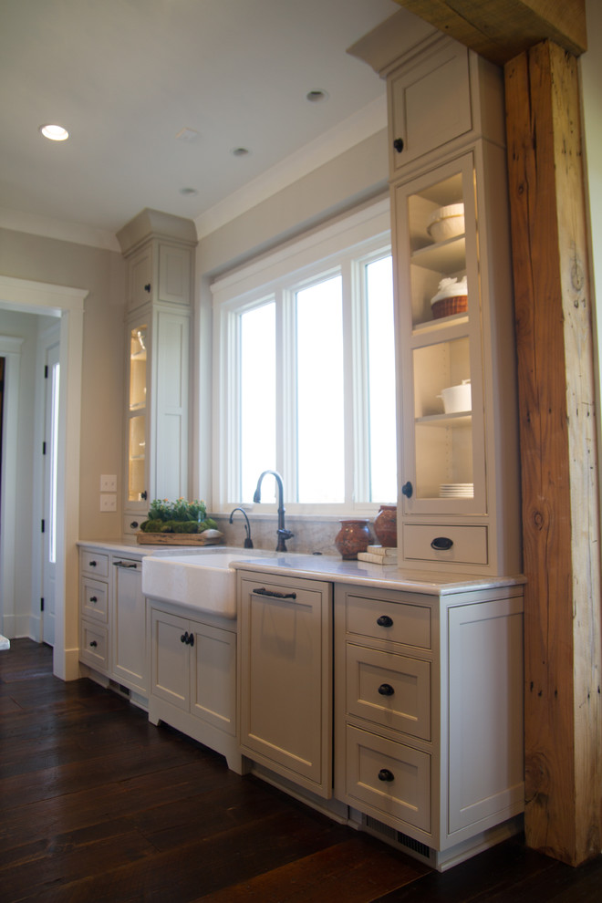 This is an example of a rural kitchen in Other with a belfast sink, beaded cabinets, beige cabinets, ceramic splashback, integrated appliances, dark hardwood flooring and an island.