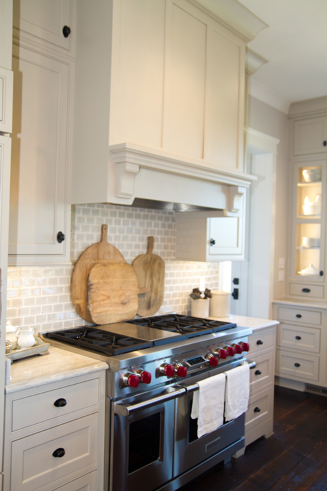 Inspiration for a farmhouse kitchen in Other with a belfast sink, beaded cabinets, beige cabinets, ceramic splashback, integrated appliances, dark hardwood flooring and an island.