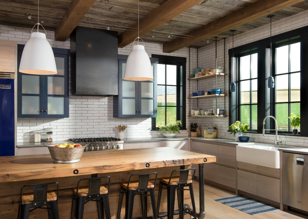 Example of a large cottage l-shaped light wood floor and brown floor eat-in kitchen design in Seattle with a farmhouse sink, flat-panel cabinets, light wood cabinets, soapstone countertops, white backsplash, ceramic backsplash, stainless steel appliances, an island and gray countertops