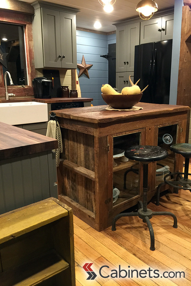 Foto di una cucina stile rurale di medie dimensioni con lavello stile country, ante in stile shaker, ante grigie, elettrodomestici neri e parquet chiaro