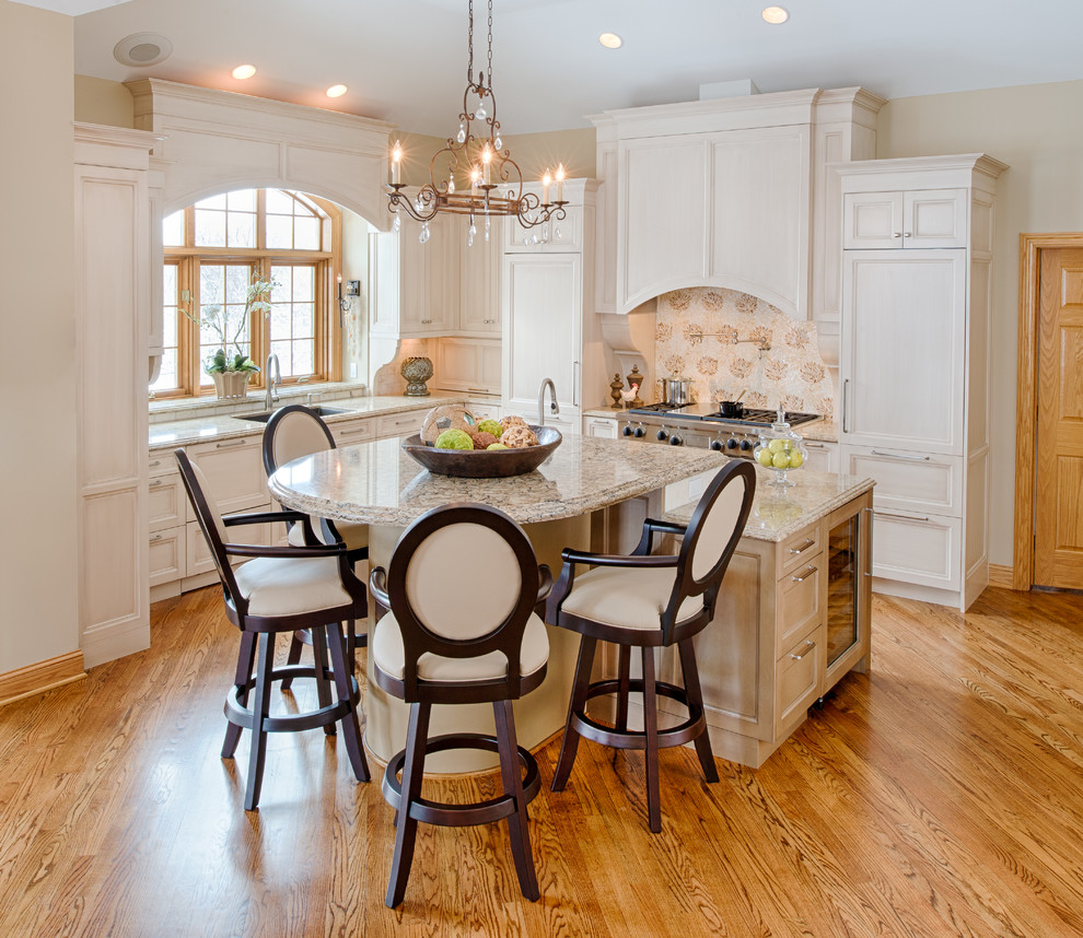 Inspiration for a mid-sized transitional l-shaped light wood floor eat-in kitchen remodel in Minneapolis with an undermount sink, white backsplash, ceramic backsplash, paneled appliances, an island, raised-panel cabinets, white cabinets and granite countertops