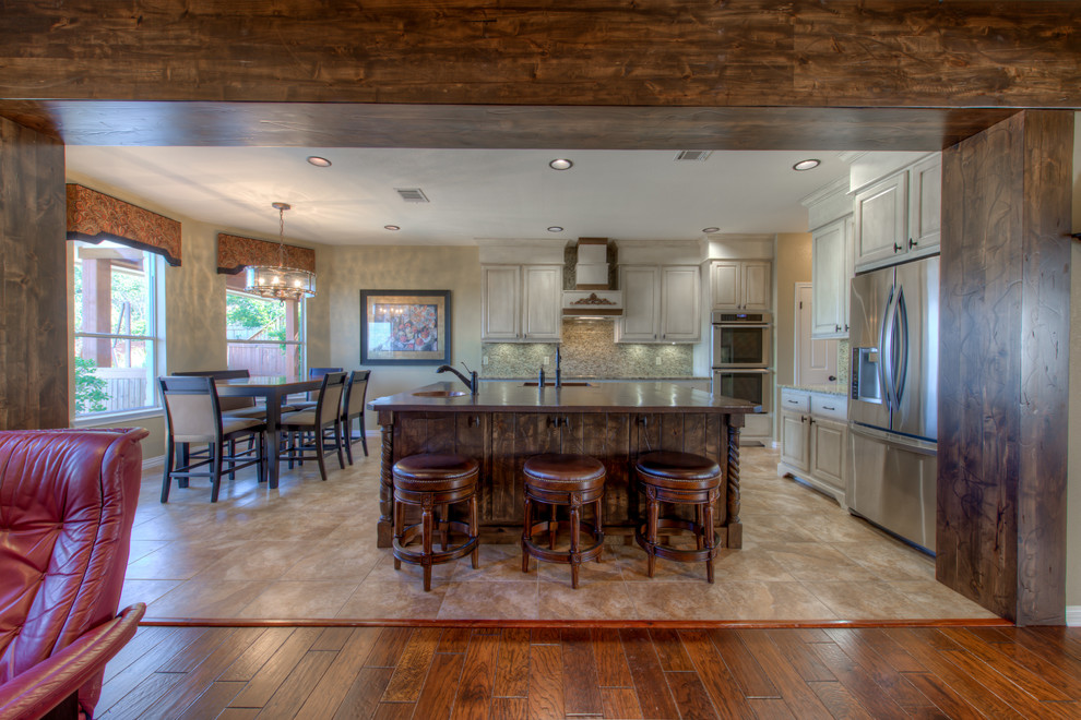Example of a mid-sized mountain style l-shaped eat-in kitchen design in Austin with a single-bowl sink, wood countertops, stainless steel appliances and an island