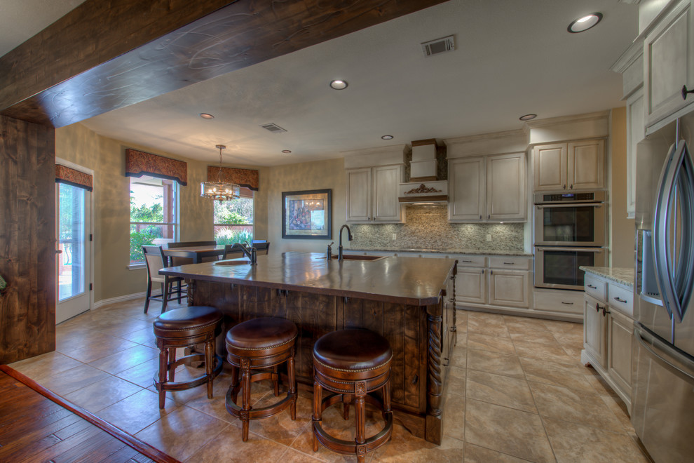 Example of a mid-sized mountain style l-shaped eat-in kitchen design in Austin with a single-bowl sink, wood countertops, stainless steel appliances and an island