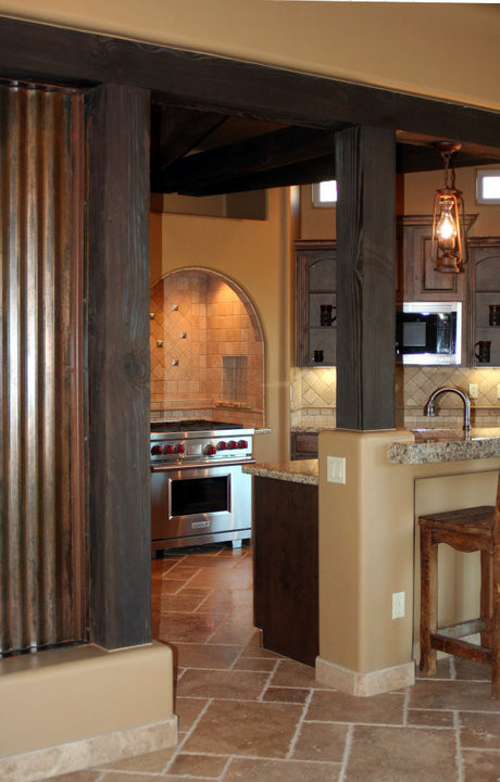 Idéer för ett mellanstort rustikt kök, med en rustik diskho, luckor med glaspanel, skåp i mellenmörkt trä, granitbänkskiva, beige stänkskydd, stänkskydd i metallkakel, rostfria vitvaror, travertin golv och en köksö