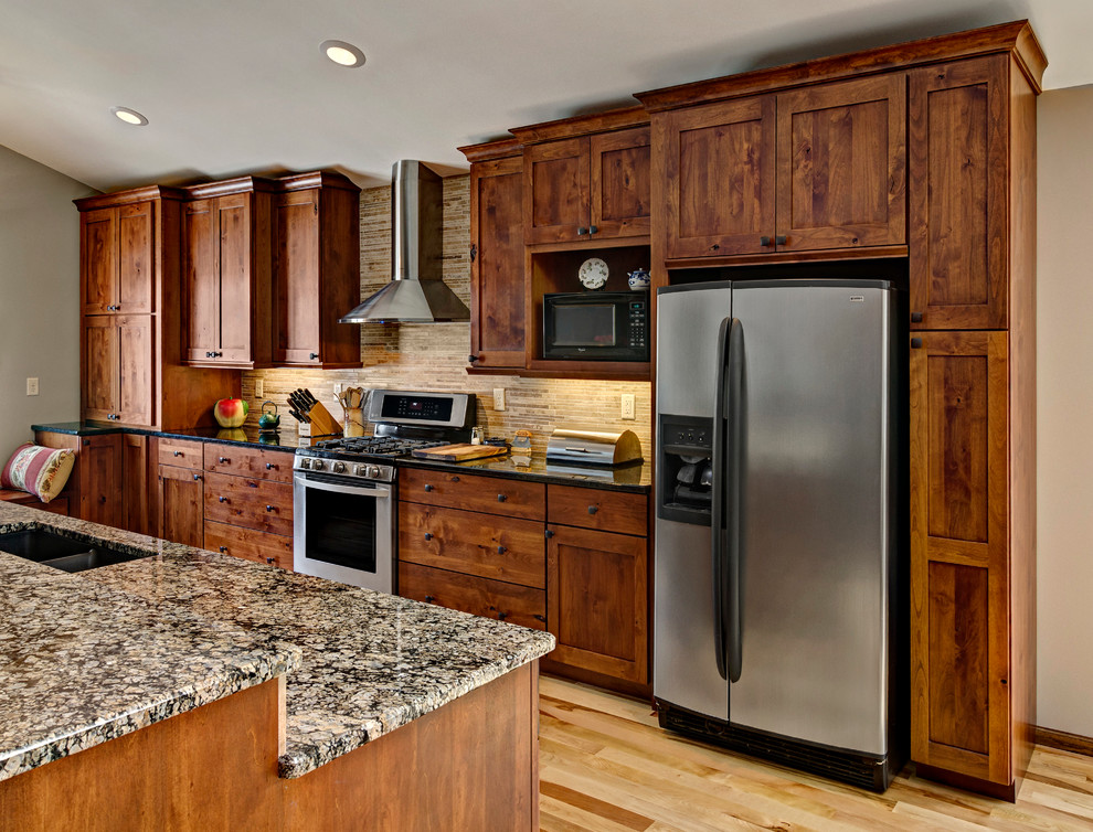 Example of a mountain style single-wall eat-in kitchen design in Minneapolis with an undermount sink, shaker cabinets, medium tone wood cabinets, soapstone countertops, beige backsplash and stainless steel appliances