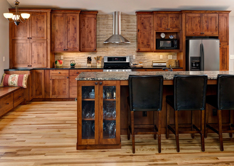 Idée de décoration pour une cuisine américaine linéaire chalet en bois brun avec un évier encastré, un placard à porte shaker, un plan de travail en stéatite, une crédence beige et un électroménager en acier inoxydable.