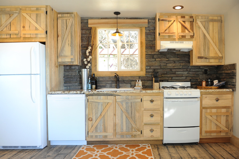 Diseño de cocina lineal rural con fregadero encastrado, puertas de armario de madera clara, salpicadero marrón, electrodomésticos blancos y pared de piedra