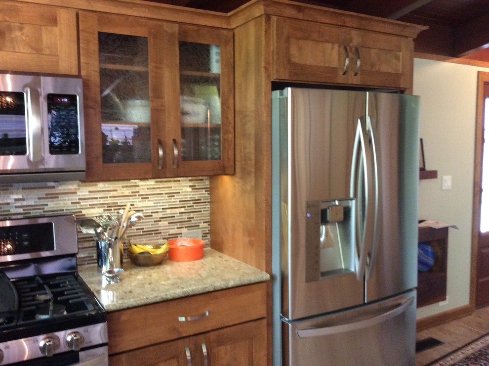 Rustik inredning av ett kök och matrum, med luckor med glaspanel, skåp i mellenmörkt trä, bänkskiva i kvarts, flerfärgad stänkskydd, stänkskydd i mosaik, rostfria vitvaror och en halv köksö